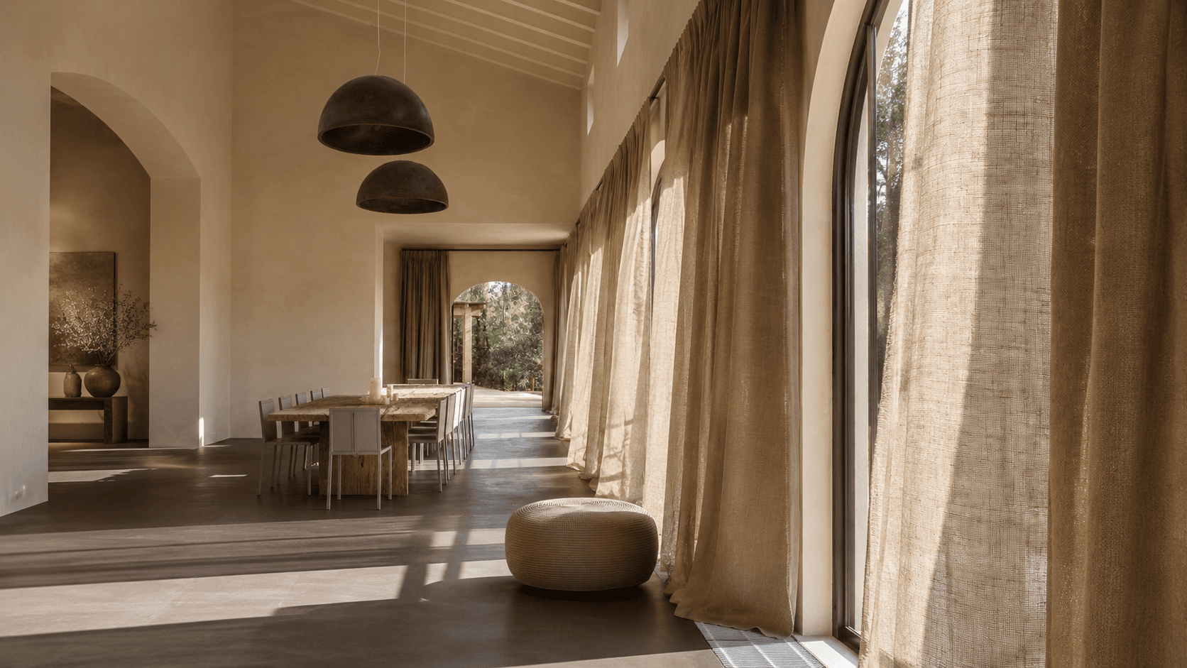 Comedor cálido con cortinas de lino y ventanales arqueados